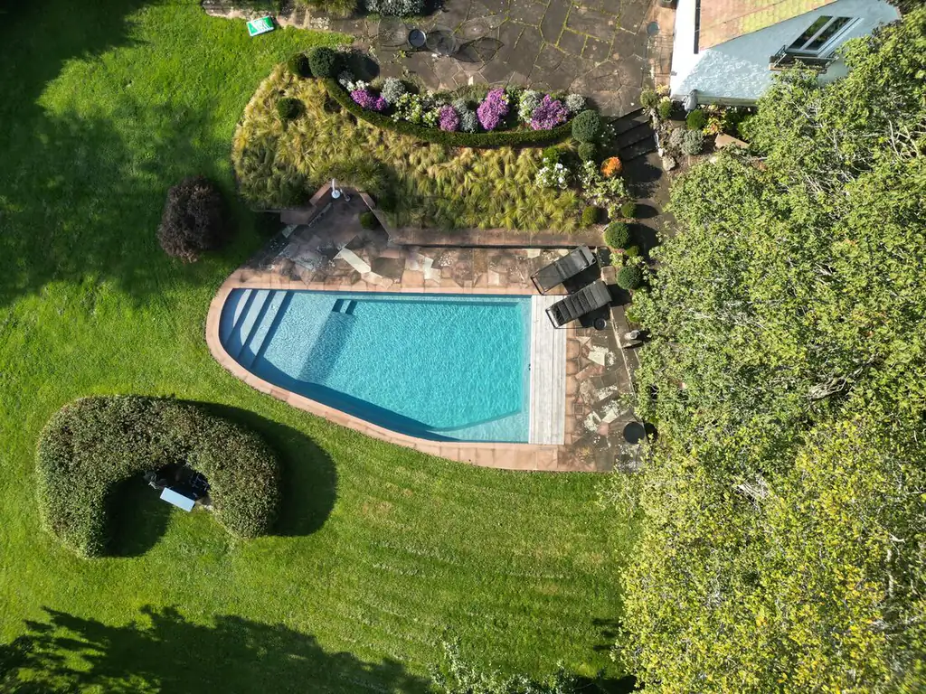 Aerial view of a pool in a landscaped garden with lawn and hedge