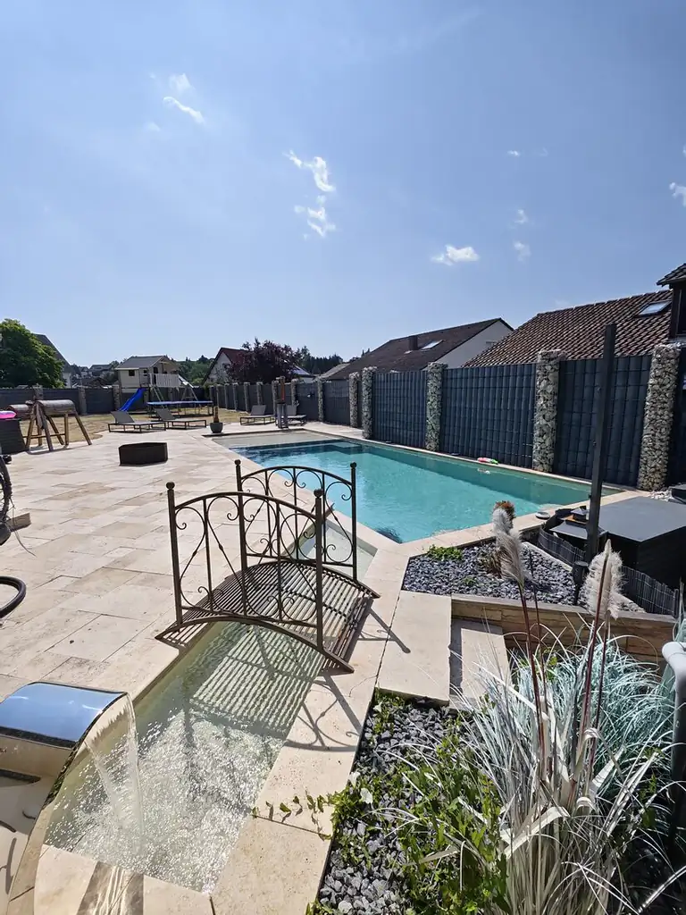 Pool with travertine terrace, ornamental bridge and stainless steel waterfall, built by SK Pools