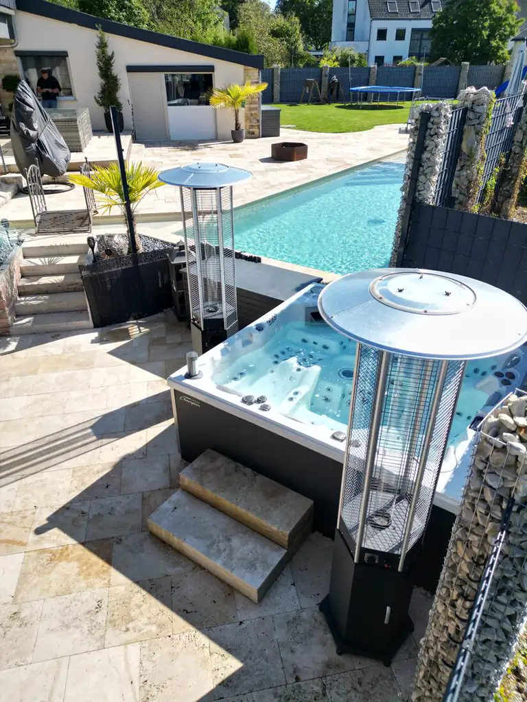 Whirlpool with timber steps on the travertine terrace beside the pool, with patio heaters