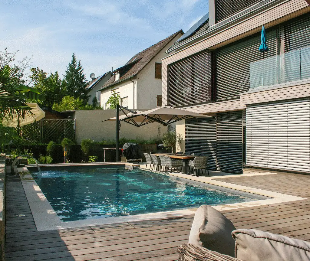 Pool with timber deck and parasol in front of the house facade in Villingen-Schwenningen
