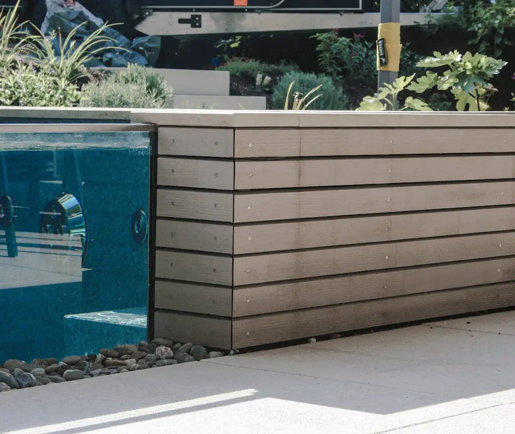 Glass wall of the pool with timber cladding and pebble bed in Villingen-Schwenningen