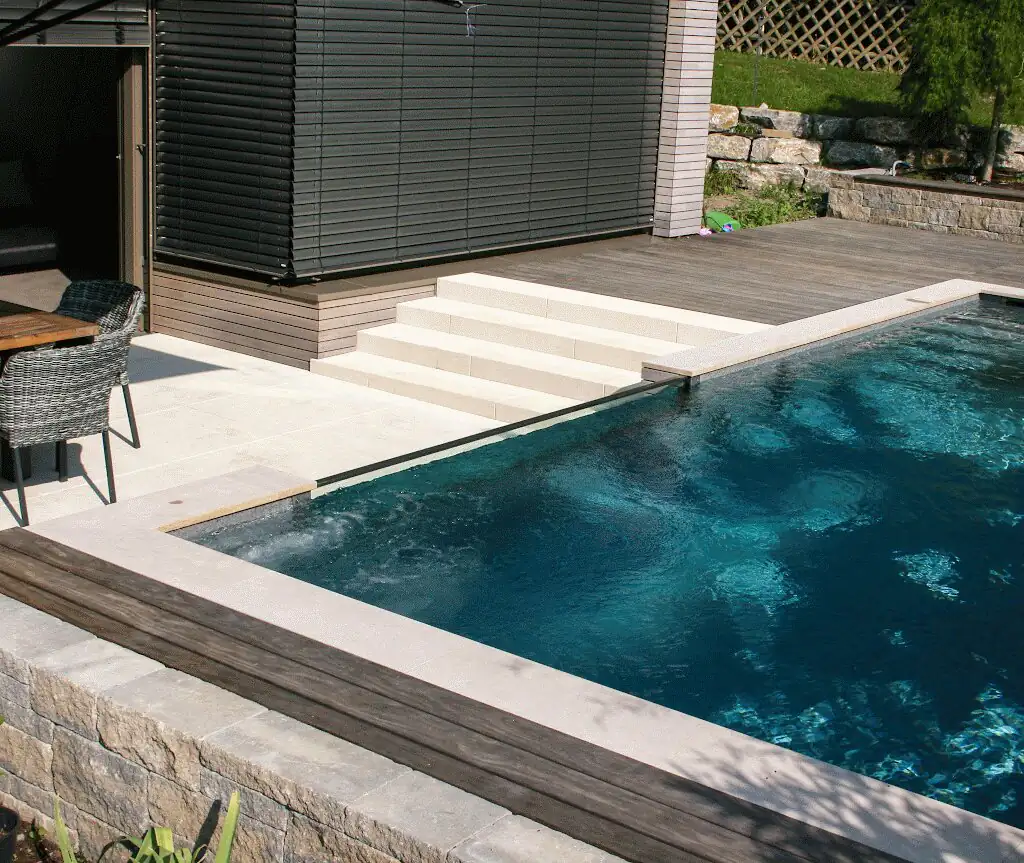 Pool with natural stone edge and timber steps in front of the house in Villingen-Schwenningen