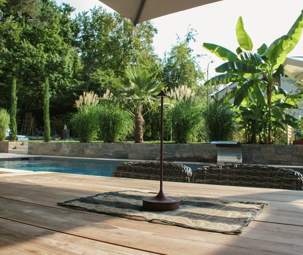 Timber deck with lamp, pool, palms and banana plants behind in Villingen-Schwenningen