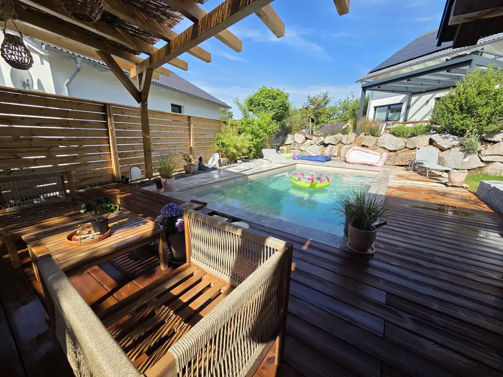 Lounge area on the timber deck overlooking the pool and natural stone wall in Villingen-Schwenningen