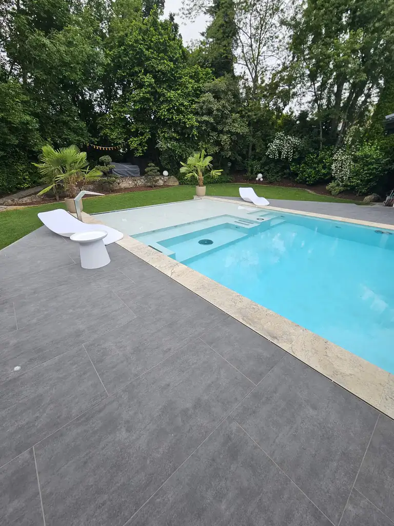 Pool with entry steps and white loungers in front of the garden in Villingen-Schwenningen